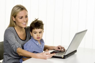 Mother and son at the computer, symbol of working from home, family and career, double burden