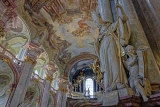 Majestic baroque St. Nicholas Church interior with a large statue and intricate frescoes under