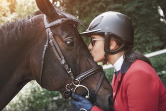 A young girl talking and kissing her horse. She loves the animals and joyfully spends her time in