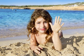 Little girl greeting hand gesture in sandy beach of Ibiza Cala Conta