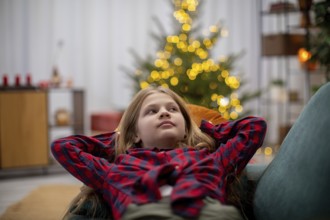 A joyful child relaxes in a cozy, warm setting, surrounded by festive decorations and glowing