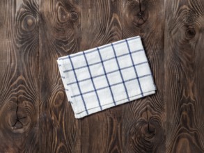 View from above on brown wooden table with linen kitchen towel or textile napkin. Blue tablecloth