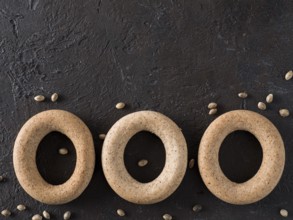 Ring-shaped cracknel with whole grain hemp seed flour and hemp seeds on black background.