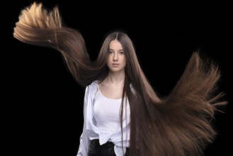 Beautiful brunette with long flying hair on a dark background