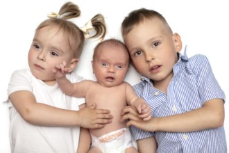 Brother and sister lying together with a newborn baby. Three small children of different ages.