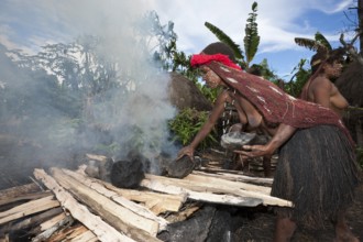 Dani Stamm heats stones for an earth oven, Baliem Valley, West Papua, Indonesia, Asia