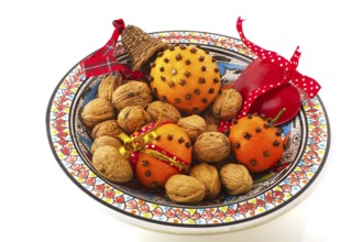 Orange with cloves and walnuts on bowl isolated over white