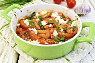 Shrimp and tomatoes baked with feta cheese in a roasting pan on a towel, parsley and garlic on a