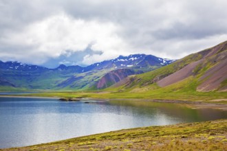 Cold summer in Iceland. Smooth water of the cold fjord reflects clouds