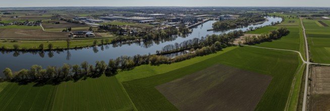 Aerial view of a river course (Danube) through fields, with industrial areas in the background,