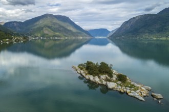 A tranquil lake with a small island surrounded by majestic mountains, their reflections captured in