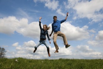 Happy jumping couple outdoor in the fields