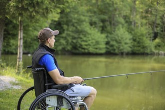 Happy and young disabled or handicapped man fishing at a lake in nature. Popular sport for