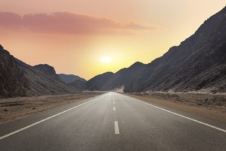 Sunrise over road through mountains in desert of Egypt