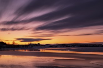 Sunset in Heidmork lake with a long exposure and clouds in moviment, Iceland, Europe