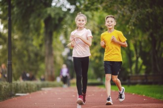 Sports and fitness in adolescence. Caucasian twins boy and girl run on the jogging track in the