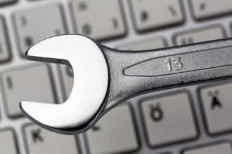 A spanner as a tool on a computer keyboard. Symbolic photo for data protection, online crime, and