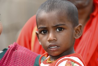 Coastal temple of Mahabalipuram, Mamallapuram, A child in red clothes with a curious and serious
