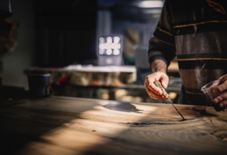 Hands skillfully using a woodworking tool on a table in a creative space with a warm atmosphere