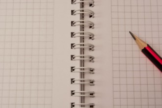 White empty notebook with pencil on top of it