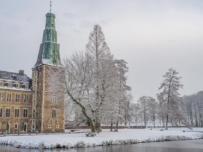 Castle in winter, surrounded by snow-covered trees, with a frozen lake in the foreground, Raesfeld,