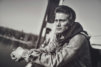 Thoughtful guy standing on the bridge looking down on the river