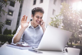 Happy handsome businessman looking at computer screen while typing something on laptop keyboard