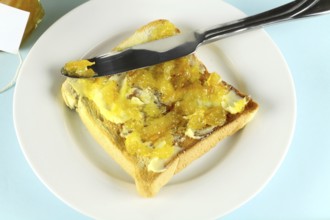 Orange marmalade spread on a slice of toast with butter