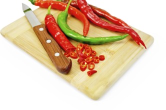 Hot pepper red and green with a knife on a wooden board isolated on white background