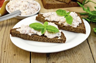 Sandwiches on two pieces of rye bread with cream of salmon and mayonnaise, basil, knife, napkin on