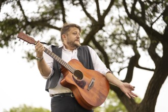 Musician gesturing while singing and playing guitar