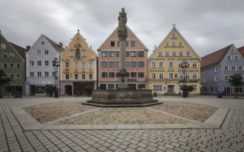 An empty market square with a statue surrounded by pastel-coloured historic buildings, Old Town