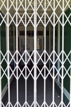 A shop is closed by a scissor gate. Symbol photo for shop opening hours