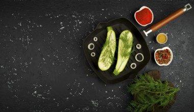 Fresh green zucchini in a pan on a dark table. The view from the top. Copy space