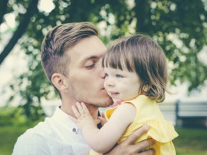Close up of father holding his crying daughter. Dad kissing his little daughter