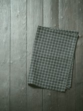 Dark wooden table with balck and white dark linen kitchen towel or textile napkin flat lay. Dark