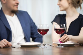 A man and a woman sit at a table. Both are elegantly dressed. On the table are two plates and two