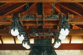 A huge wrought iron chandelier with round white balls. Metal pendant chandelier in the knight's