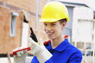 An apprentice / trainee. Construction worker on building site with helmet. Austria