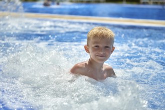 Young boy kid child eight years old splashing in swimming pool having fun leisure activity. Boy