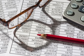 A calculator lies on the figures of a balance sheet and statistics. Symbol photo for turnover,