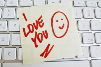 A note lies on the keyboard of a computer as a reminder: I love you Austria