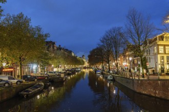 Quiet canal at night with reflective lights and surrounding buildings, Amsterdam, Netherlands