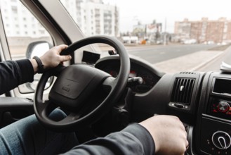 Driver in a vehicle navigating through urban roads during daytime