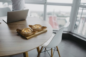 Bread dishes on a table with a laptop and chair in a modern space