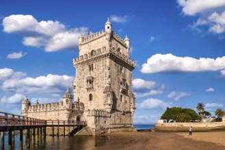 Belem tower and wooden bridge to it, Lisbon, Portugal at blue summer day sky with clouds. Medieval