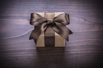 Square vintage gift box with brown ribbon on old wooden board holiday concept