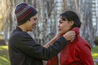 Young woman wrapping a scarf around her girlfriend's neck with care