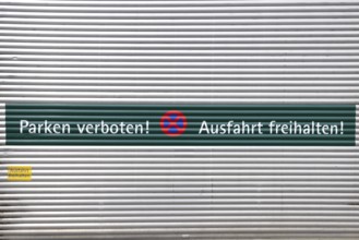 Rolltor mit der Aufschrift "Parken verboten und Ausfahrt freihalten" auf Deutsch