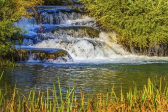 Croatia, Slunj. Little tourist town on the river Korana. Cascade waterfalls are lit by sunset rays.